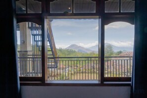 A window with a view of a mountainous landscape and a building with a staircase. - Mountain View House Kintamani (Bali)