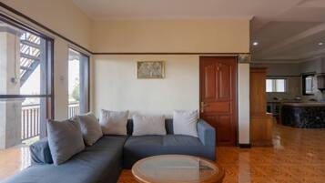 Uma sala de estar com sofá, mesa de centro de vidro e piso de madeira.