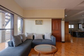 Een woonkamer met een bank, een glazen salontafel en een houten vloer.