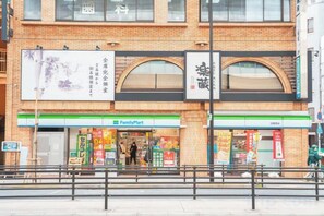 A FamilyMart store with a brick facade, large signage, and a storefront with visible merchandise. - YOOSUU Nippori self-help Apartment (Tokyo)
