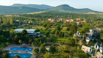 An aerial view of a resort with multiple dome-shaped cabins, a swimming pool, and surrounding greenery.