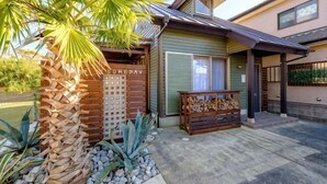 Une maison avec un portail en bois, un banc et un palmier.