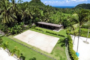 A tennis court surrounded by lush greenery and a small building with a roof. - Neano Escape (Bali)