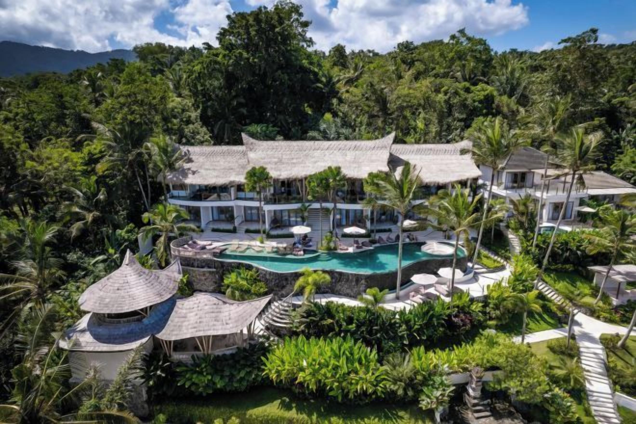 Resort com piscina, vários edifícios e vegetação exuberante.