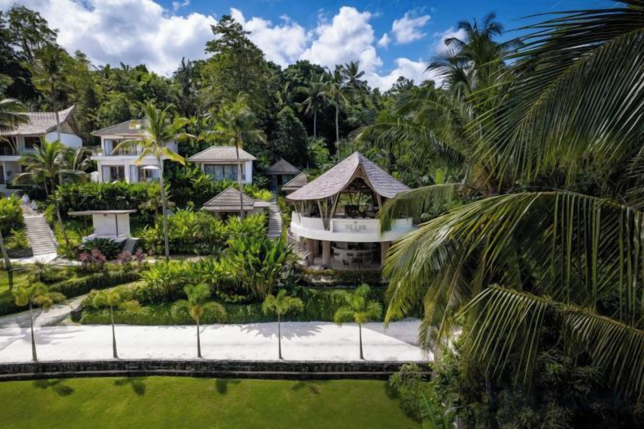 A resort with multiple villas, a swimming pool, and lush greenery.