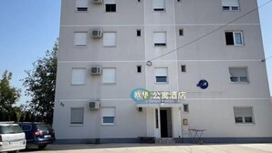Ein mehrstöckiges Hotel mit schlichter Fassade, Klimaanlagen und einem Schild, das es als öffentliche Unterkunft kennzeichnet.
