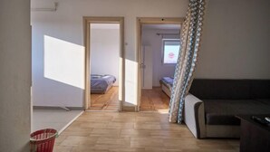 Ein offener Wohnbereich mit einer Couch, einem Bett und einem fensterbepflanzten Fenster.