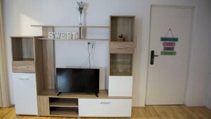 Ein Zimmer mit integriertem Fernseher, einem weißen Kleiderschrank und einer Tür mit angenietetem Schild.