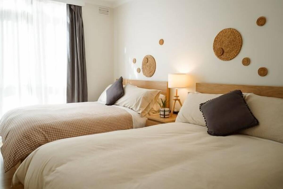 Une chambre d’hôtel avec deux lits, une table de chevet avec une lampe et des éléments de décoration murale.