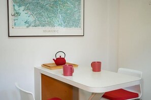 A white table with a red teapot and two pink mugs on a tray, a framed map of Melbourne on the wall, and a white chair. - Darling Street Residence - Self Check-In Only (South Yarra)