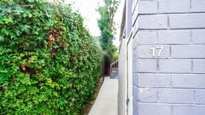 A narrow pathway flanked by a hedge and a building with the number 17. - Darling Street Residence - Self Check-In Only (South Yarra)