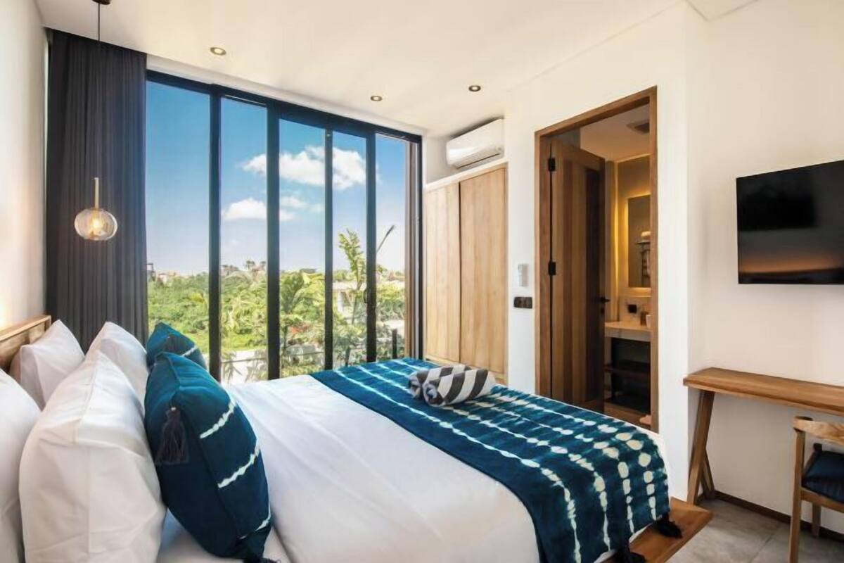 A modern hotel room with a large bed, a desk, and a TV.
