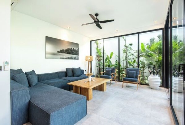 A modern living room with a sectional sofa, a wooden coffee table, and two armchairs. - NOMA 6 DOLLAR (Bali)