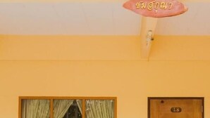 A room with a wooden bench, a window with curtains, and a door labeled "L8". - Ban Silachol (Rayong)