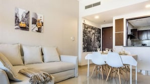 A modern living room with a sofa, a dining table with chairs, and a kitchen area with cabinets. - bnbme Great Value Apt in Dubai Sports City (Dubai)