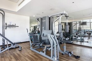 A gym with various exercise machines, a mirror, and a wooden floor. - bnbme Great Value Apt in Dubai Sports City (Dubai)