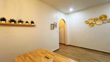 A room with a wooden table, a shelf with plants, and a wall with decorative plates.