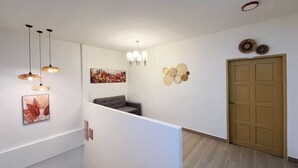 A modern interior with a staircase, pendant lights, wall art, and a door.