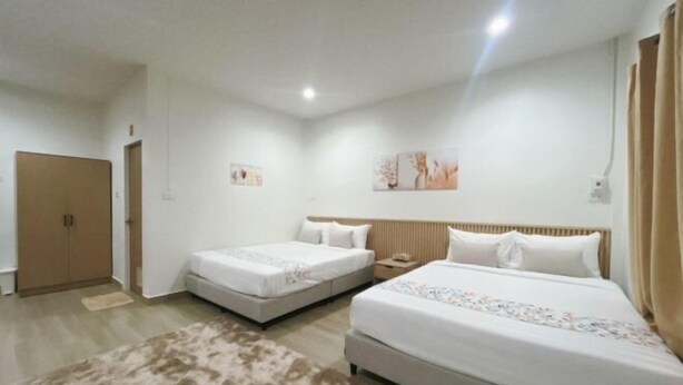 A hotel room with two beds, a wardrobe, and a small rug.