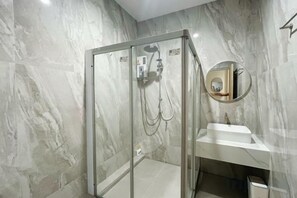 A bathroom with a glass-enclosed shower, a white sink, and a marble wall. - Sleeping Shine by DeliZia Homestay (9-10 Persons) (Satun)