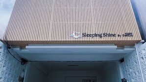 A building with a wooden slatted facade and a sign that reads 'Sleeping Shine by Delizia.'