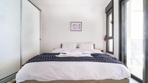A modern bedroom with a bed, a framed picture on the wall, and a window. - Achziv Beach Haven 3BR Apartment by Sea N' Rent (Nahariyya)
