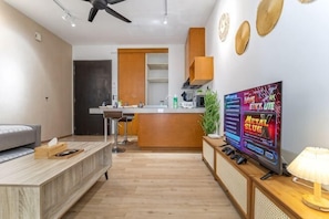A modern living room with a sofa, a coffee table, a TV, and a kitchen area with a bar counter. - [NEW] Private Jacuzzi Near Velocity Mall MRT (Kuala Lumpur)