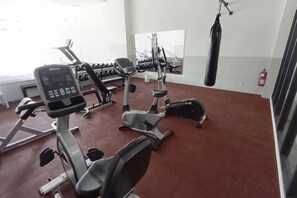 Een sportschool met cardiotoestellen, gewichthefriapparatuur en een bokszak.