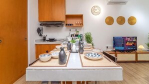 Une cuisine compacte avec des meubles en bois, une cuisinière intégrée et un coin repas avec une table dressée pour deux personnes.