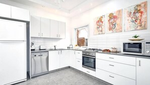 A modern kitchen with white cabinets, stainless steel appliances, and abstract art on the wall. - Heart of Tel-Aviv Spacious Stay by Sea N' Rent (Tel Aviv)