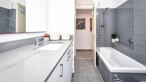 A modern bathroom with a large mirror, a double sink, a bathtub, and a shower. - Heart of Tel-Aviv Spacious Stay by Sea N' Rent (Tel Aviv)