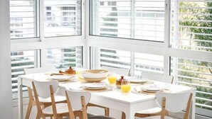 A dining area with a white table and chairs, a bowl, plates, and a glass of orange juice. - Heart of Tel-Aviv Spacious Stay by Sea N' Rent (Tel Aviv)
