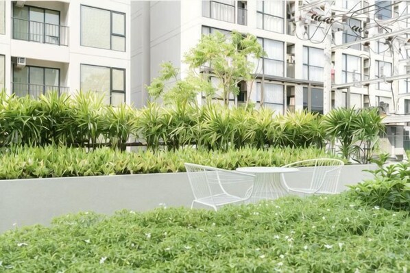 Un jardin sur le toit, agrémenté de verdure et d’une chaise en métal blanche.