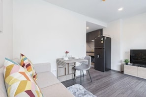 Ein modernes Wohnzimmer mit Sofa, Essbereich, Küche und Fernseher.