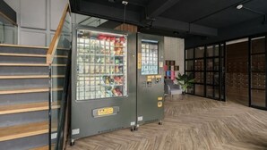 A modern interior with a vending machine, wooden flooring, and a staircase.