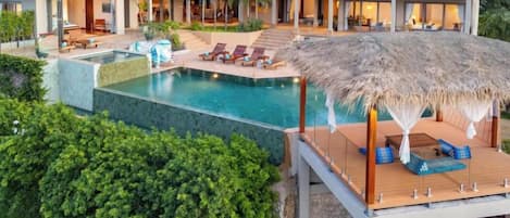 Un resort con piscina, sillas de descanso y una estructura de techo de paja.