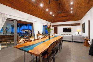 A dining area with a wooden table, chairs, and a view of the outdoors. - Baan Faasai 5-Bedroom Hillside Seaview Pool Villa (Koh Samui)
