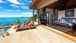 Een moderne kamer met een grote glazen deur die uitkomt op een balkon met uitzicht op een prachtig zeegezicht.