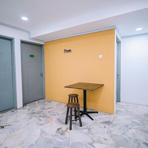 A room with a yellow wall, a table, and a stool. - Swing & Pillows @ Seri Kembangan (Balakong)