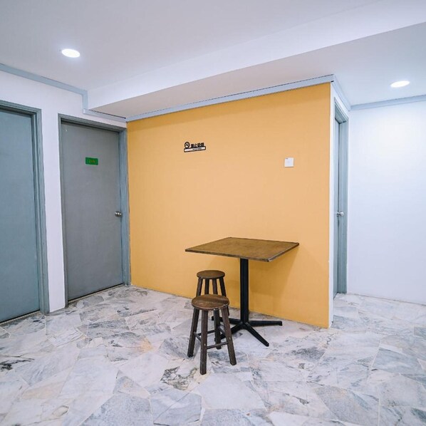 Una habitación con una pared amarilla, una mesa y un taburete.