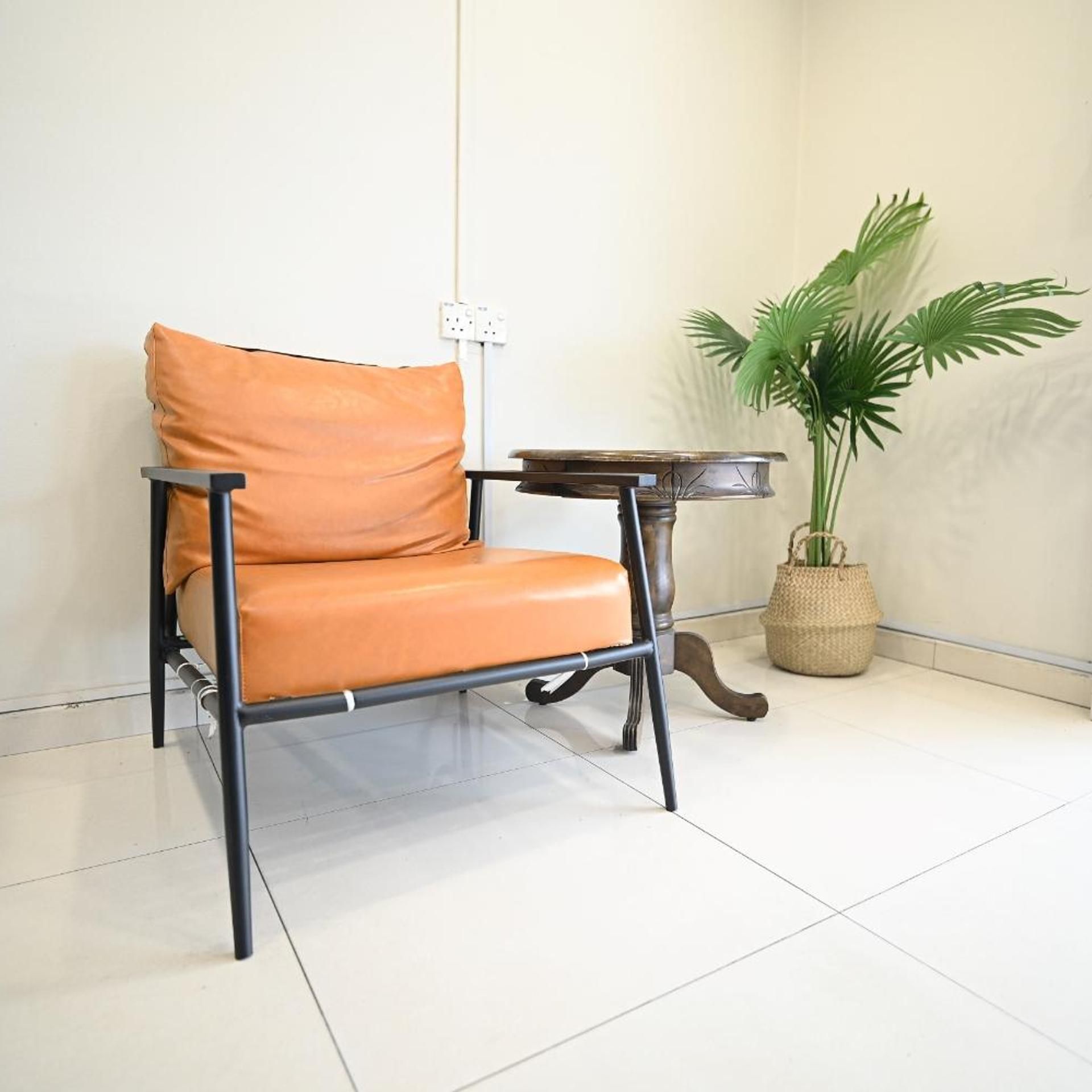 A chair with a cushion, a small round table, and a potted plant in a corner.