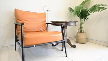 A chair with a cushion, a small round table, and a potted plant in a corner.