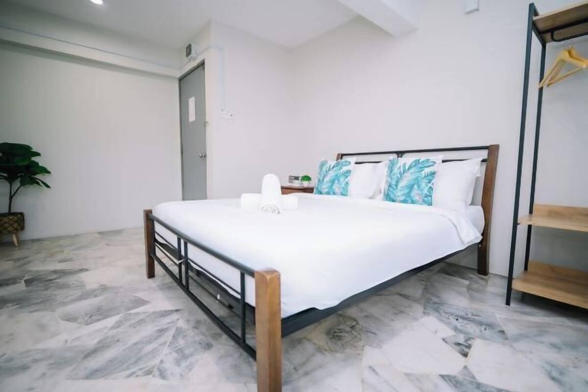 A bedroom with a bed, a wooden headboard, a nightstand, a plant, and a wardrobe.