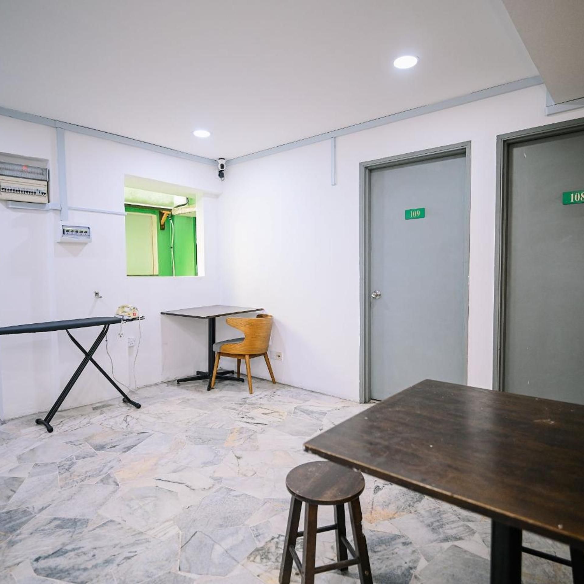 A room with a table, a chair, a stool, a door, and a window.