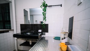Een moderne badkamer met een zwarte wastafel, witte betegelde muren, een spiegel en een groene plant.