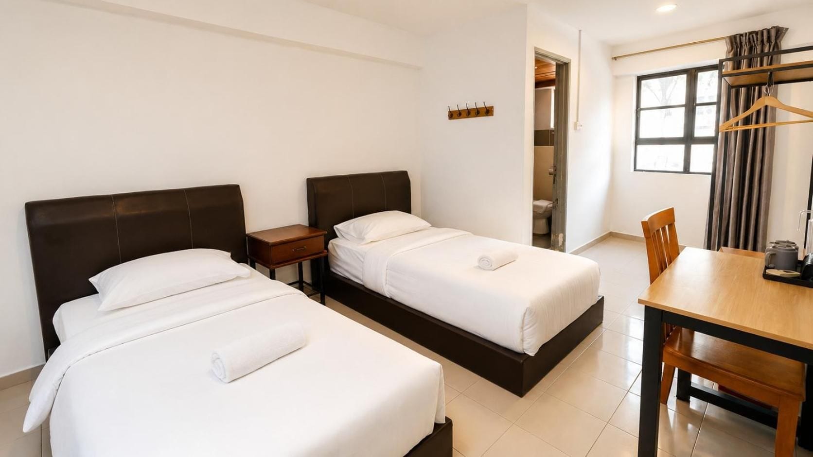 Una habitación de hotel con dos camas, una mesita y una silla.