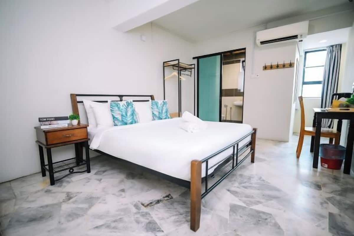 A modern bedroom with a bed, a nightstand, a desk, and a chair.