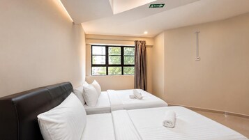 Habitación de hotel con dos camas, una ventana con cortinas, una lámpara en el techo y un letrero de salida de emergencia instalado en la pared.