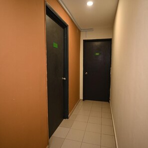 Un pasillo con dos puertas, una marcada con el número 112, y suelo de baldosas.