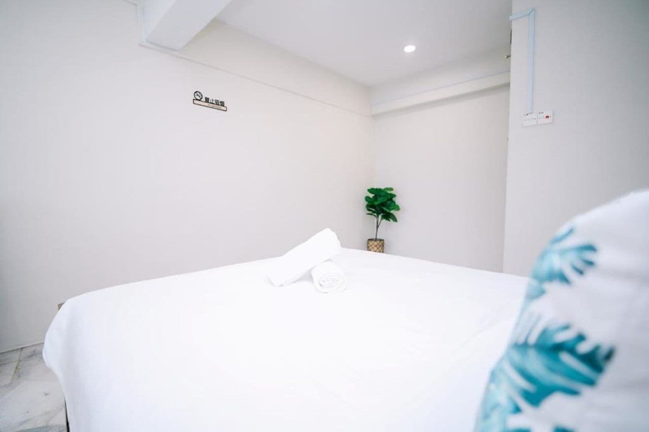 A hotel room with a neatly made bed, a small potted plant, and a sign on the wall.